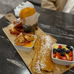 Tulua Bistro - Small chef's board: French toast, bacon, hash browns, shrimp and grits, oblong pancakes stuffed with bacon, fruits