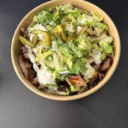 Mixed grill shawarma bowl with lettuce, pickles, and garlic sauce