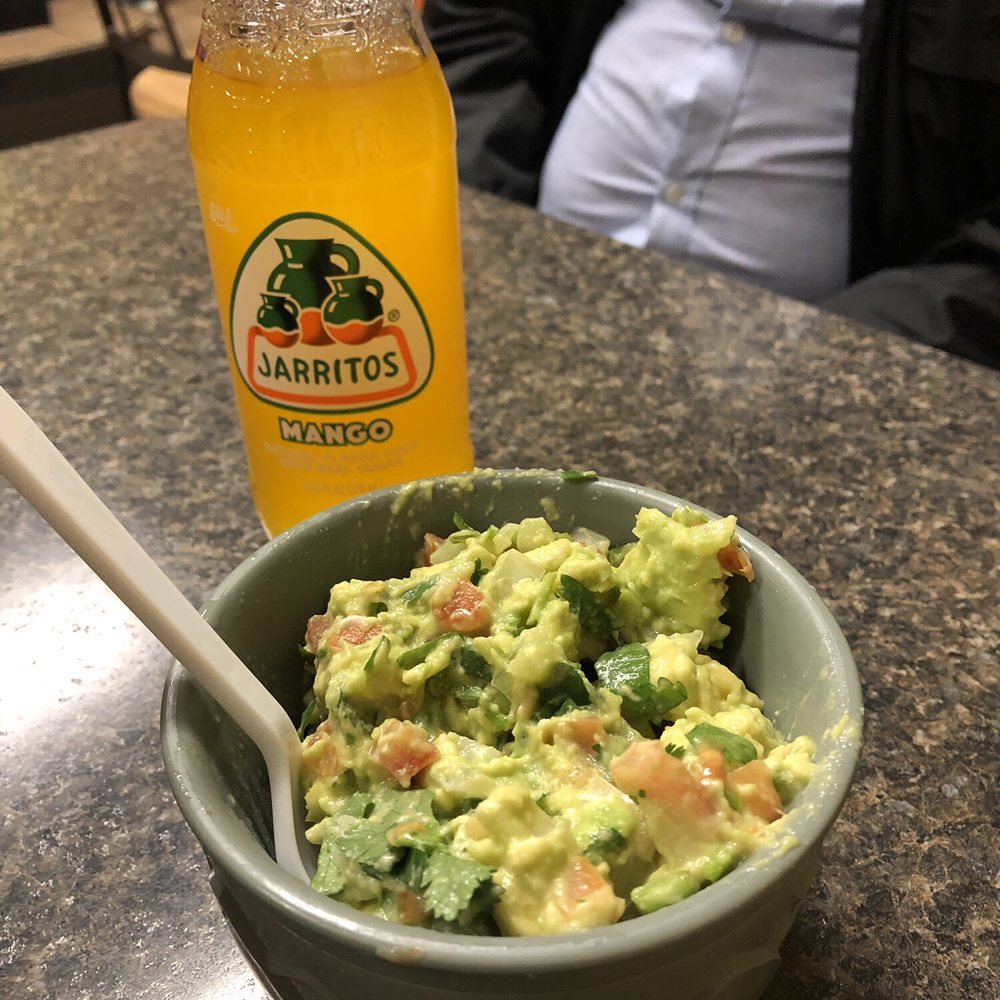 a bowl of guacamole and a bottle of soda a bowl of guacamole and a bottle of soda