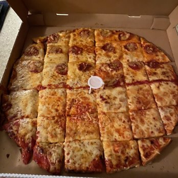 Aurelio's Pizza - a pizza in a box - A pizza with cheese and pepperoni slices is shown in an open cardboard box, cut into multiple pieces, with a small plastic pizza saver in the center. - Pizza Near Me - Mokena, Illinois