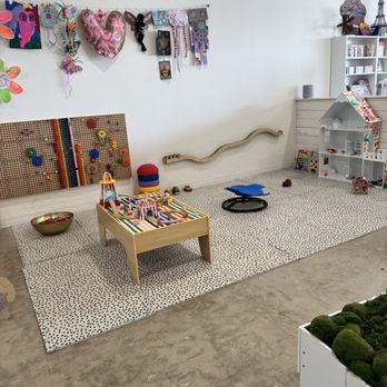 Create Studio ATX - A children's play corner features toys, craft supplies, and decorative items on the wall, with a soft rug and various play objects on the floor. - Art Supplies Near Me - Austin, Texas