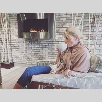 Aroma Coffee - a woman sitting on a couch in front of a fireplace - Coffee & Tea Near Me - Davenport, Iowa