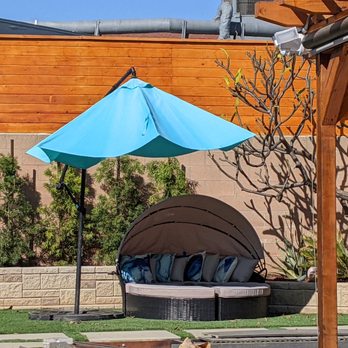 Deiby's Landscape - a patio with a blue umbrella - Landscaping Near Me