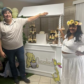 Relax We Got You Events - Father and mother of baby shower taking photo in front of candy cart that Ria built. - Balloon Services Near Me Relax We Got You Events - Father and mother of baby shower taking photo in front of candy cart that Ria built. - Balloon Services Near Me