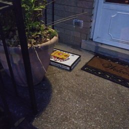 a pizza box on the ground next to a potted plant a pizza box on the ground next to a potted plant