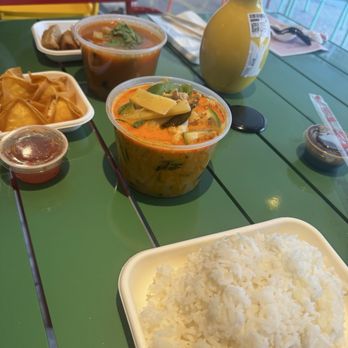 SomTam - The image shows a meal with white rice, two cups of soup, spring rolls, and dipping sauces on a green table at a restaurant. - Thai Near Me - Washington, DC, District of Columbia