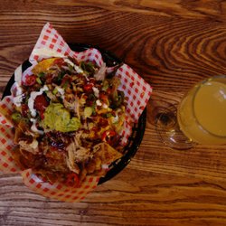 Manchester Smokehouse & Cellar - Wood fired nachos loaded with 3 cheese, salsa, guacamole & sour cream, topped with 12 hour smoked pulled pork