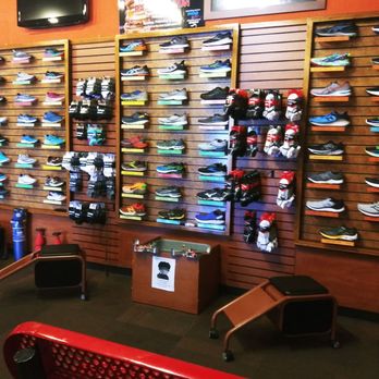 Runner's Den - A retail display of various running shoes and accessories on wooden slatwall panels in a running store. - Shoe Stores Near Me - Phoenix, Arizona