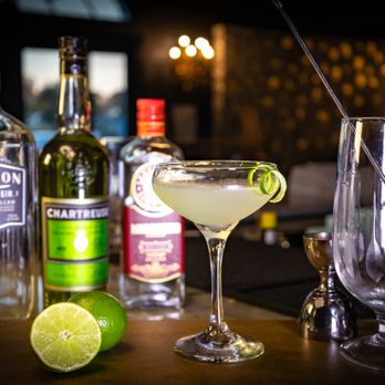 The Ruins - a glass of alcohol and a lime slice - Cocktail Bars Near Me - Lafayette, Louisiana