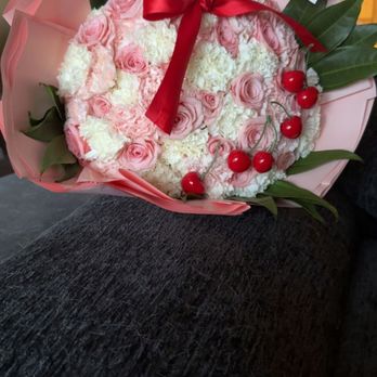 Stem Stop - Pink and white rose bouquet wrapped in pink paper with a red bow, cherries added for flare,with green leaves that frame the bouquet. - Florists Near Me