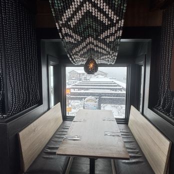 Diego's - A restaurant booth features a wooden table with black cushioned benches on either side, positioned by a window showing a snowy outdoor scene. - Mexican Near Me - Newport, Rhode Island