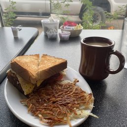 Bacon, egg, and tomato sandwich with hash browns on the side. Bacon, egg, and tomato sandwich with hash browns on the side.