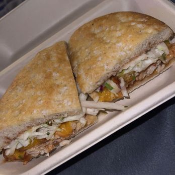 Urbane Cafe - Santa Maria BBQ Sandwich - A sandwich with toasted bread, shredded lettuce, cheese, and meat filling is placed in a white container, likely served at a restaurant or cafe. - Sandwiches Near Me - Temecula, California