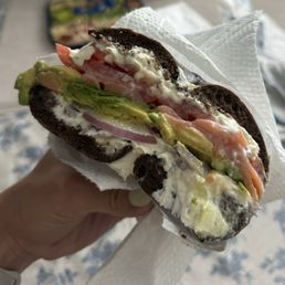 Pumpernickel bagel with salmon, avocado, tomato, onion and cream cheese Pumpernickel bagel with salmon, avocado, tomato, onion and cream cheese