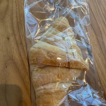 Starbucks - croissant - Three croissants are inside a clear plastic bag placed on a wooden table, with visible layers and a golden-brown color. - Coffee & Tea Near Me - Plainview, New York