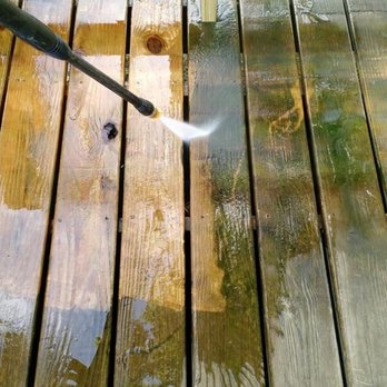 Wolf Pride - a person using a high pressure hose to clean a wooden deck - General Contractors Near Me