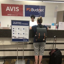 Budget Car Rental - No mask, standing in between the barriers, with a sign saying we wear mask and use barriers.