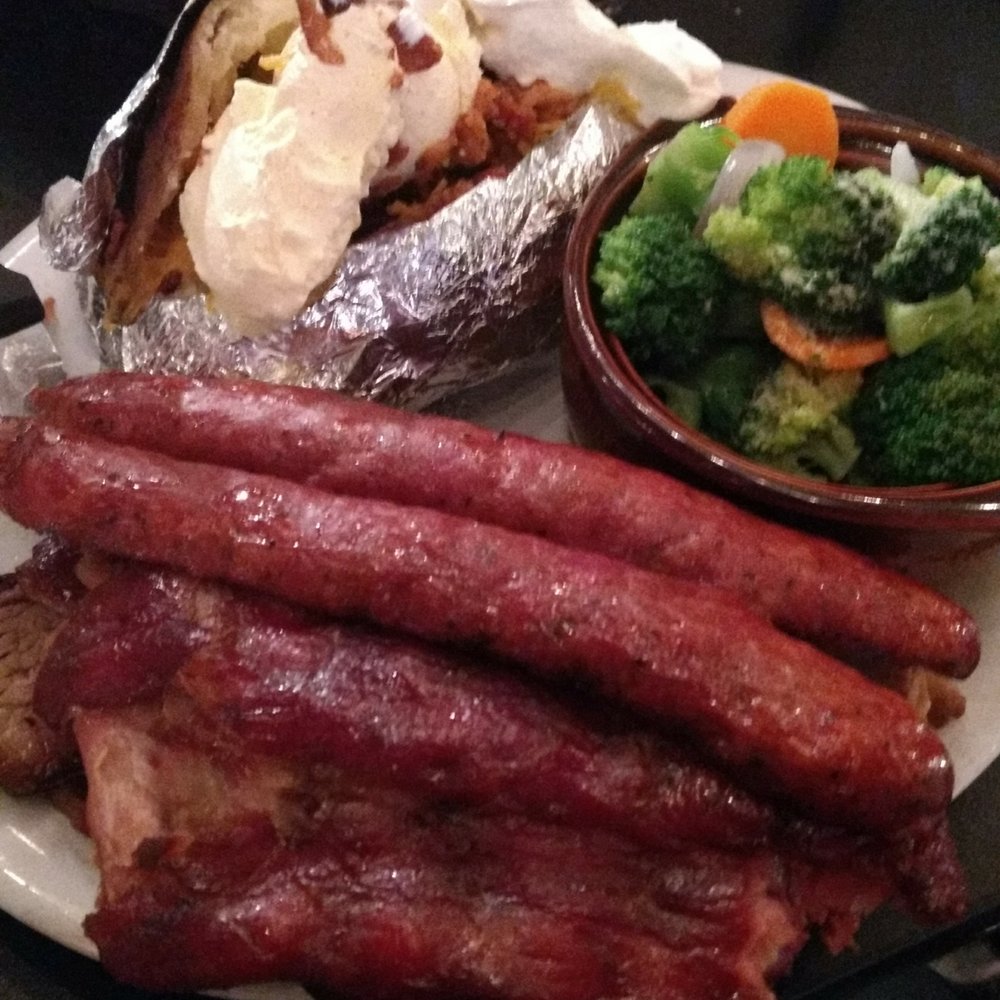 Three meat plate with baked potato and veggies.