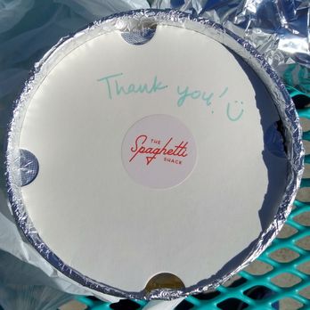 The Spaghetti Shack - Spaghetti packaging - A round pizza box with a handwritten 'Thank you! :)' note and The Spaghetti Shack logo in the center, placed on a picnic table. - Italian Near Me - Tempe, Arizona