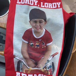 birthday t-shirt - A red T-shirt displays a printed photo of a young boy in a red shirt, with text reading 'LORDY, LORDY' and 'ADAM'S 40.'
