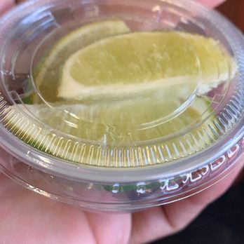 Carnitas El Rincon - Alma - a hand holding a plastic container with a slice of lemon on it - Tacos Near Me - San Jose, California Carnitas El Rincon - Alma - a hand holding a plastic container with a slice of lemon on it - Tacos Near Me - San Jose, California