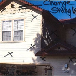 Prior to repair. Cracks in siding below window and above the garage to the right.
