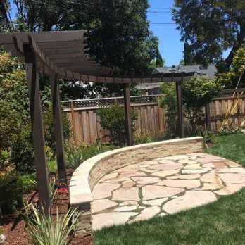 KB Landscape - a stone patio with a pergolated arbor - Landscaping Near Me
