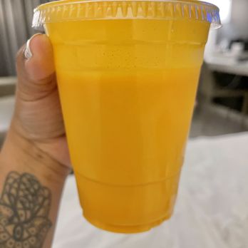 Tandoori Pizza - a hand holding a cup of orange juice - Pizza Near Me - Hawthorne, California