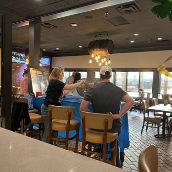 Barrel House - Several individuals are gathered around a table with a blue tablecloth, engaging in a raffle or drawing activity inside a restaurant or pub. - American Near Me - Bloomington, Illinois