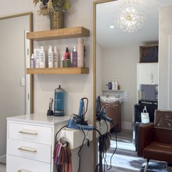 Modern styling station at Jane Michael Hair Studio in Menifee, CA, featuring premium haircare, gold mirrors and a warm, inviting feel.