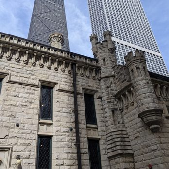 Chicago Water Tower - Older and newer: architecture is what Chicago's all about! - A stone building with medieval-style turrets and narrow windows is shown with Chicago's modern skyscrapers in the background. - Art Galleries Near Me - Chicago, Illinois