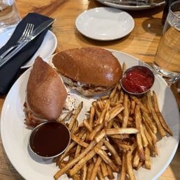 Smoked chicken sandwich with blueberry barbecue sauce on the side and fries