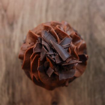 Mini Cakes - a chocolate frosted cupcake on a wooden table - Cupcakes Near Me