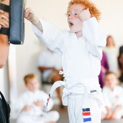 SwiftKick Martial Arts Carlsbad - Young white belt martial artist punching a pad.