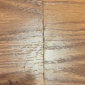 Royal Home Flooring - The image depicts a wooden surface with visible scratches, gouges, and surface damage. The wood grain is apparent, and the damage appears as multiple linear scratches and indentations across the surface, indicating wear or impact. The lighting highlights the texture and imperfections of the wood. - Flooring Near Me - Bridgeview, Illinois