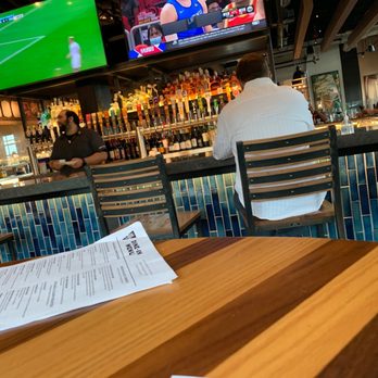 BJ's Restaurant & Brewhouse - a man sitting at a bar with a menu in front of him - American Near Me - Orange, Ohio