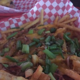 a basket of french fries with cheese and green onions