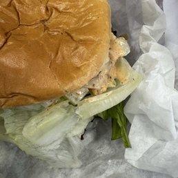 Redhot ranch RHR Burger and Fries - A burger with a toasted bun, lettuce, and sauce is partially wrapped in white paper, placed on a gray surface.