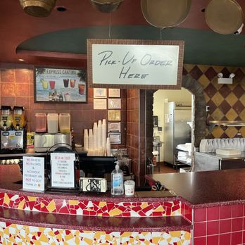 Besa Mi Taco - pick up area - Counter with a sign for pick-up orders at Besa Mi Taco, featuring drink dispensers, cups, and signs about ID and alcohol policies. - Mexican Near Me - Itasca, Illinois