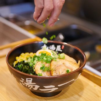 Kyuramen x TBaar - Jackson - a person sprinkling rice on a bowl - Ramen Near Me - Jackson, Mississippi