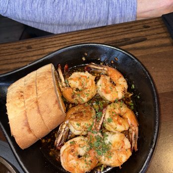 Beacon 70 Restaurant - A black bowl contains cooked shrimp garnished with herbs, accompanied by slices of bread, on a wooden table at a restaurant. - New American Near Me - Brick, New Jersey