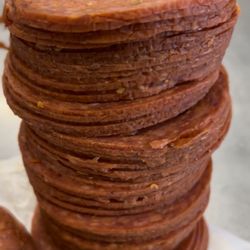 Bun Appetit! - Small batch old world pepperoni being sliced for our pepperoni rolls- available at the Saturday Farmers Markets