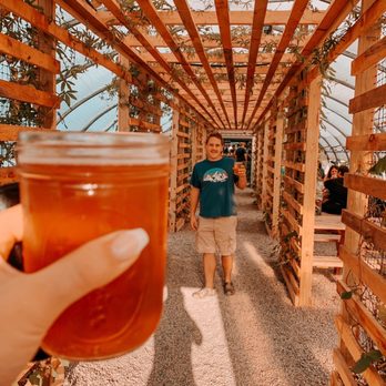 The Greenhouse Cidery - a man holding a jar of cid - Cideries Near Me - Chatham, New York The Greenhouse Cidery - a man holding a jar of cid - Cideries Near Me - Chatham, New York