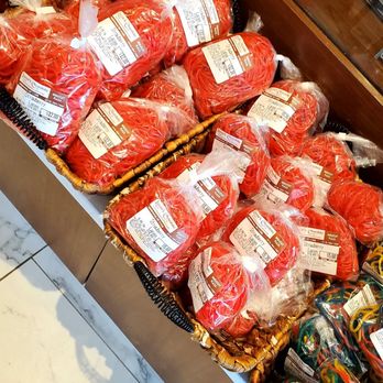 Lazar's Chocolate - Multiple bags of red-colored candies or confectionery are arranged in a basket at a store, with labels visible on each bag. - Candy Stores Near Me - Greenvale, New York
