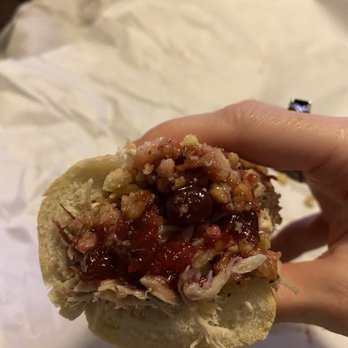 Capriotti's Sandwich Shop - Dray AF - A person holds a sandwich with shredded meat, sauce, and toppings, with a crumpled white paper background. - Sandwiches Near Me - Mesa, Arizona