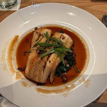 Seasons 52 - A dish with cooked fish fillet topped with green garnishes, served with a sauce on a white plate in a restaurant setting. - New American Near Me - Albuquerque, New Mexico