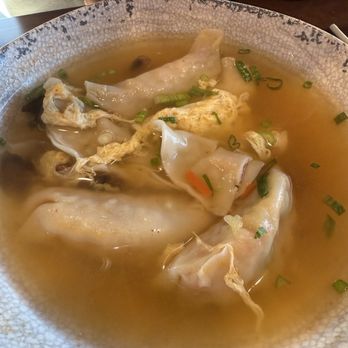 Bonchon - Dumpling soup - A bowl of dumpling soup containing broth, dumplings, and chopped green onions, served in a textured ceramic bowl. - Korean Near Me - Worcester, Massachusetts