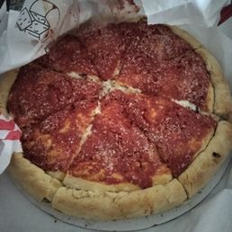 Stuffed Crust Pizza - A pizza with a thick, golden crust, topped with pepperoni slices, tomato sauce, and grated cheese, partially wrapped in paper.