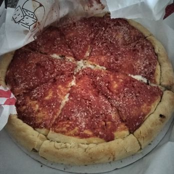 Frankie V's Bar & Grill - Stuffed Crust Pizza - A pizza with a thick, golden crust, topped with pepperoni slices, tomato sauce, and grated cheese, partially wrapped in paper. - Italian Near Me - Whiting, Indiana