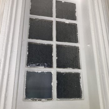 First Choice Masonry - Sloppy paint job - A rectangular window with nine individual glass panes arranged in three rows and three columns. Some panes are textured with a ripple pattern, while others are smooth. The window frame is painted white and appears to be part of an interior or exterior wall. The surrounding trim is also white, with visible molding details. The image focuses on the window, showing its design and glass variations. - Roofing Near Me